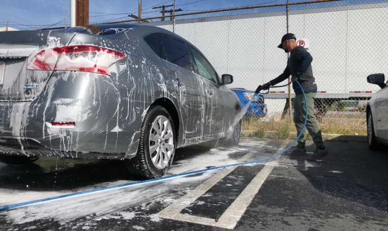 A detailer foam washing a car during an exterior wash
