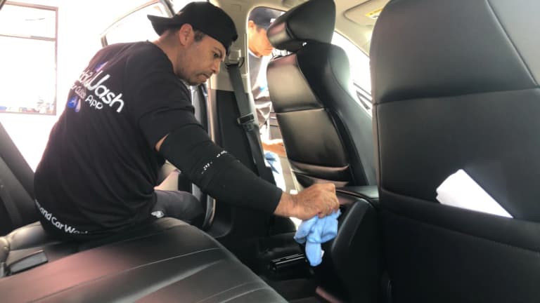 A detailer wiping down a black leather car interior
