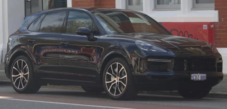 Porsche Cayenne vs Macan comparison: dark blue Cayenne SUV, front three-quarter view