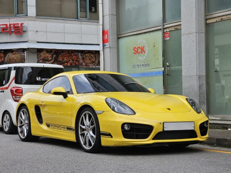 Yellow 981 Porsche Cayman S coupe parked on a city street
