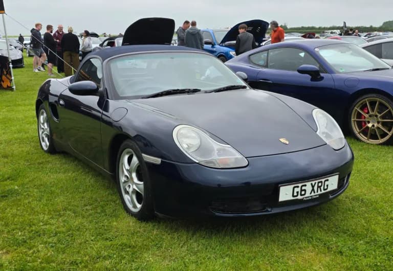 Dark blue 986 Porsche Boxster roadster with the fabric roof up at a car show