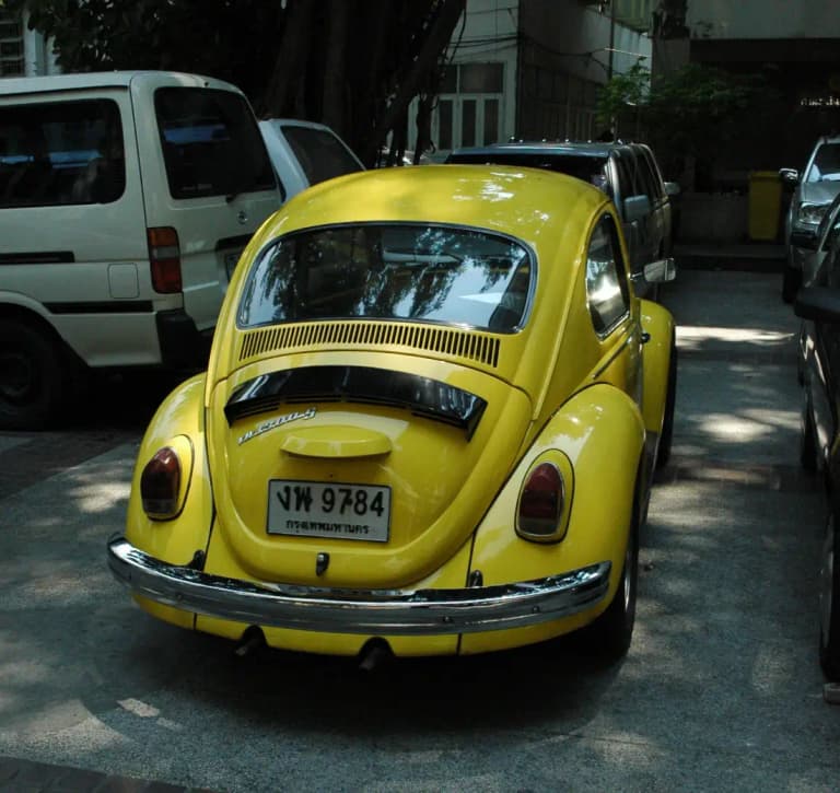Yellow classic Volkswagen Beetle with a Thai license plate parked in Bangkok