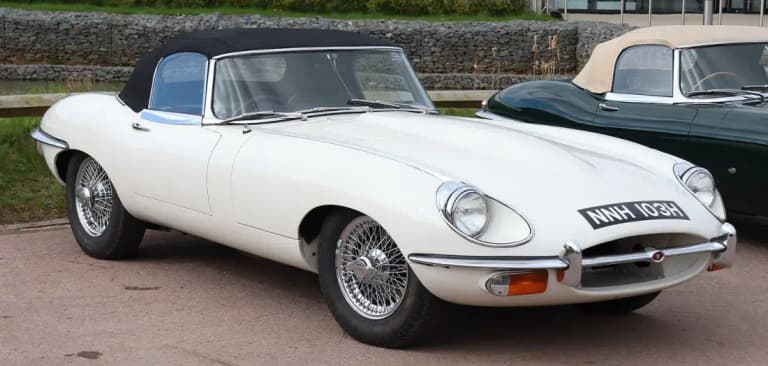 White Jaguar E-Type roadster with wire wheels parked outdoors