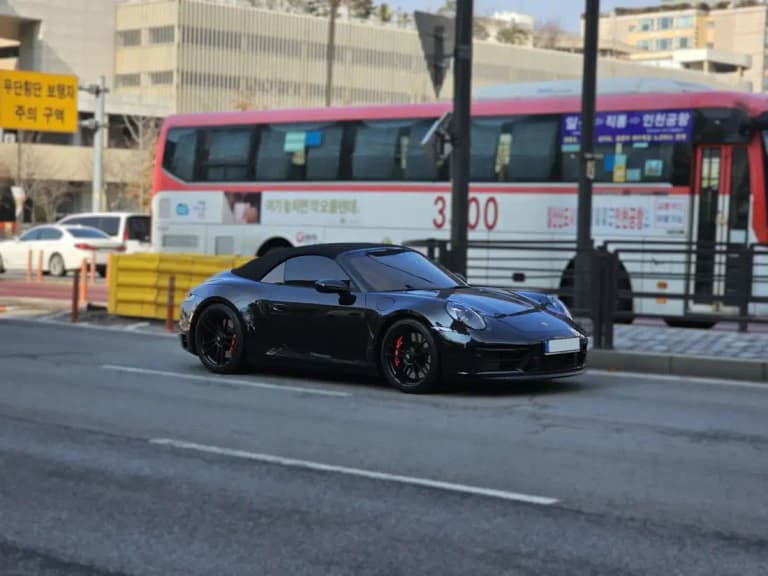 Black Porsche 992 911 Carrera 4S Cabriolet, side view in a city street