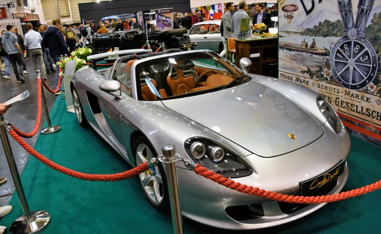 Silver Porsche Carrera GT with the roof panels removed showing the tan interior
