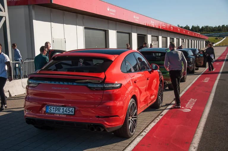 Red Porsche Cayenne Turbo Coupe at a racetrack pit lane, rear view