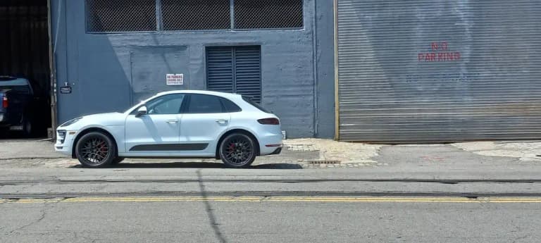White Porsche Macan GTS side profile showing the lowered stance and black side blades