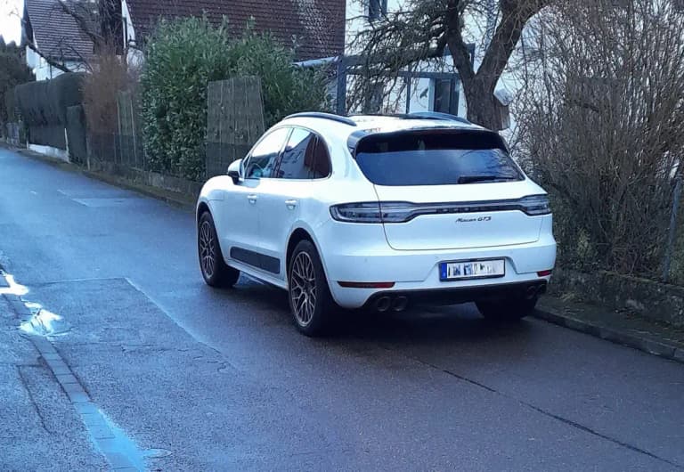 White Porsche Macan GTS rear three-quarter parked on grass at a car show