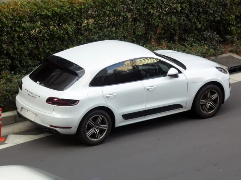 White Porsche Macan GTS rear three-quarter view on a residential street