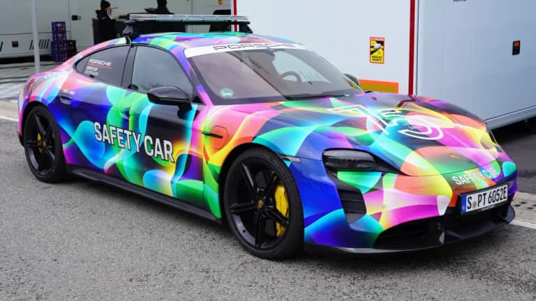 Rainbow-wrapped Porsche Taycan Turbo S race safety car with yellow brake calipers