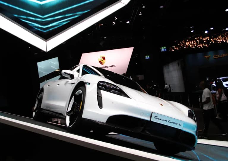 White Porsche Taycan Turbo S on a Porsche auto show stand