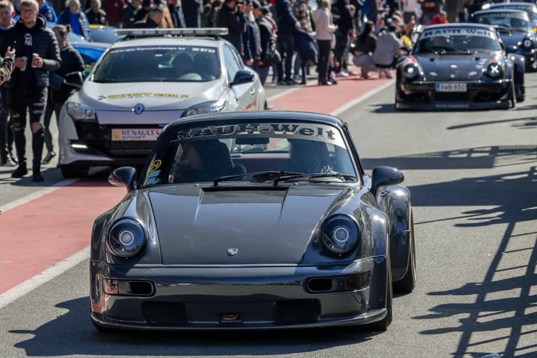 Gunmetal RWB Porsche named Bourgogne in a pit lane with another RWB behind