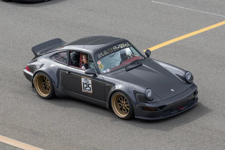 Gunmetal RWB Porsche 964 with gold wheels driving on track