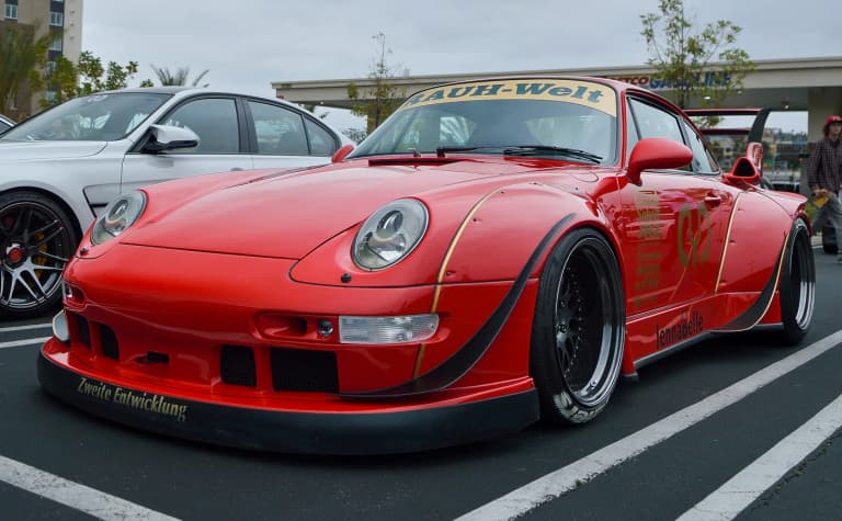 Red RWB Porsche 911 (993) with riveted widebody fenders and Rauh-Welt windshield banner
