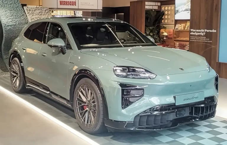 Sage green Porsche Cayenne Turbo Electric front three-quarter view in a Porsche brand store