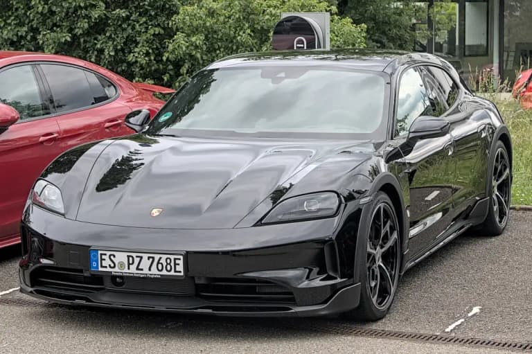 Black Porsche electric Taycan Sport Turismo parked beside a charging pillar