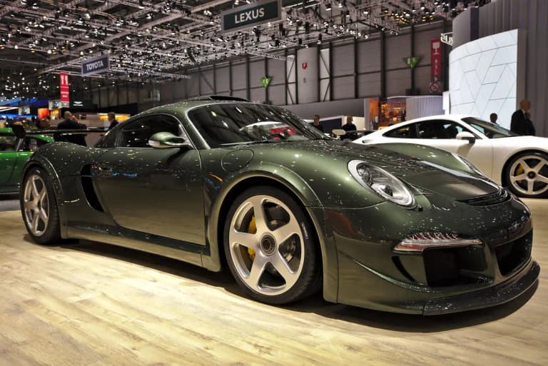 Dark green RUF CTR3 mid-engine sports car with a large fixed rear wing at a Geneva motor show