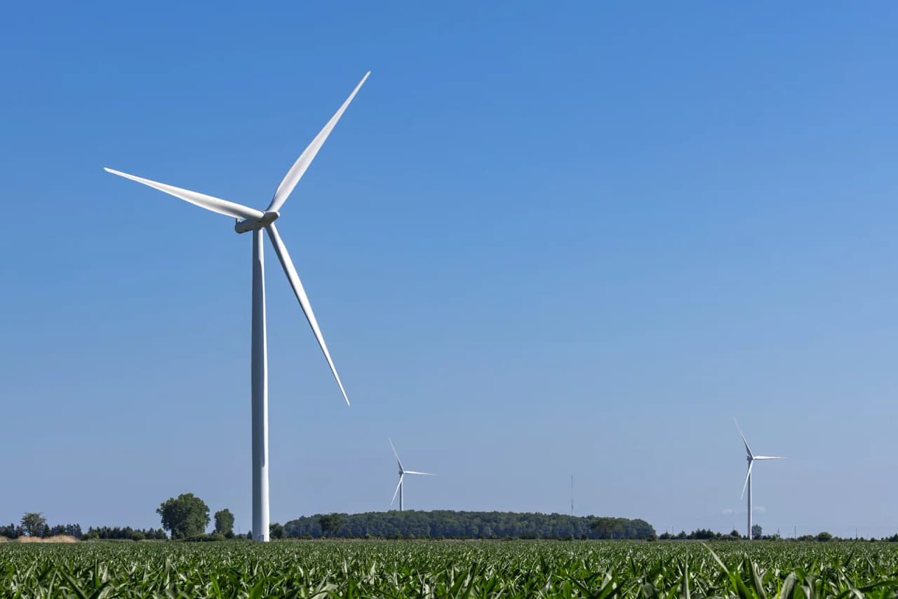 Three wind turbines above fields and a road in Essex County, Ontario