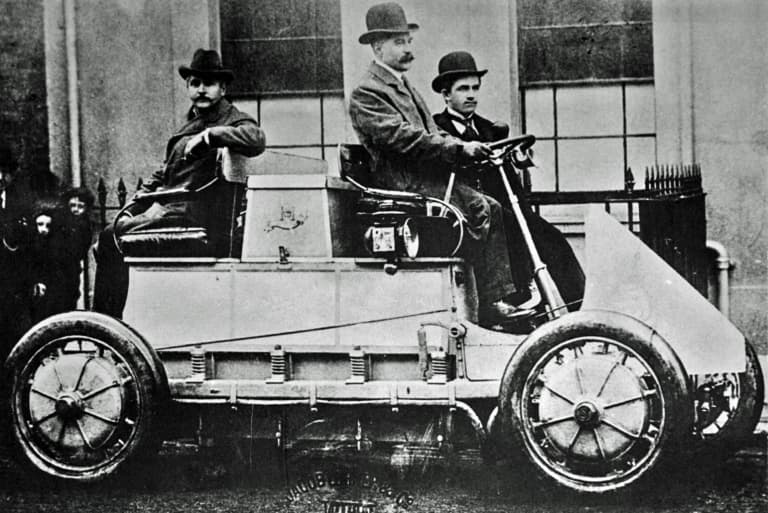 Early Lohner-Porsche racing car with Ferdinand Porsche beside the vehicle.