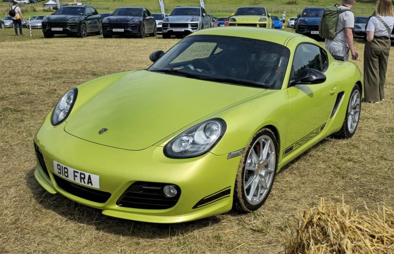 Lime green Porsche Cayman R viewed from the front on grass.