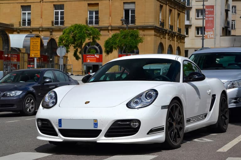 White Porsche Cayman R viewed from the rear on a city street.