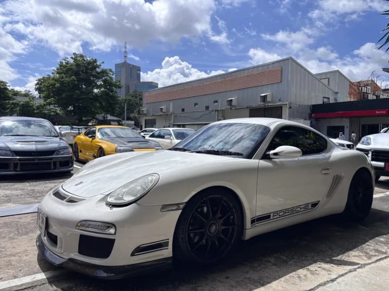 White Porsche Cayman parked at a daytime Bangkok car gathering