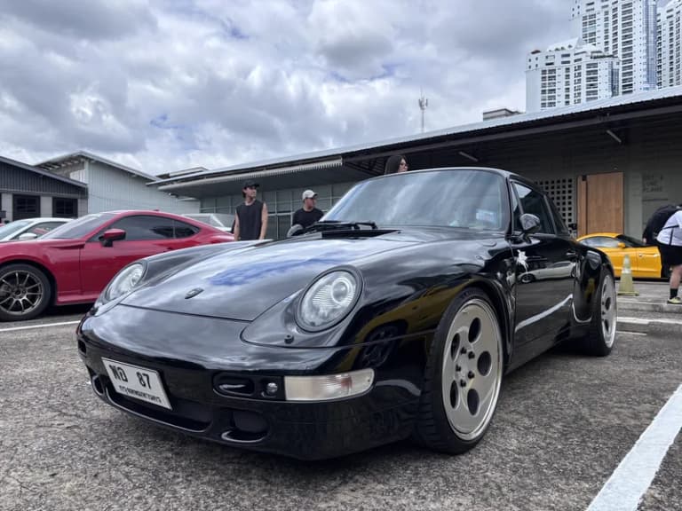 Black Porsche 911 parked at a daytime Bangkok car gathering