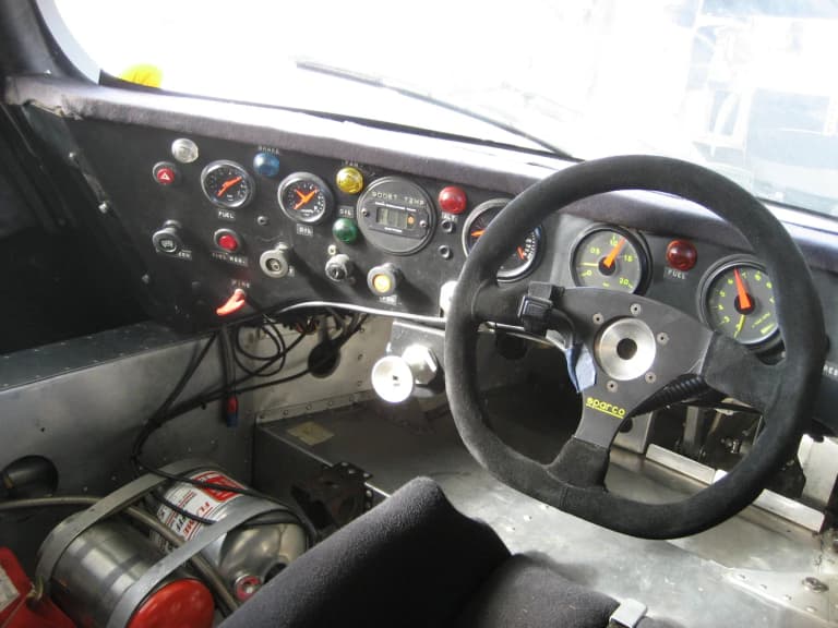 Stripped racing cockpit of a Porsche 962 with switch panel and small steering wheel
