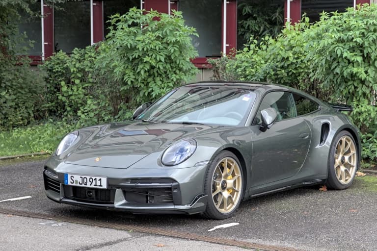 Dark grey Porsche 992 Turbo S coupe with gold wheels