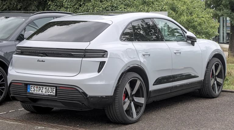 White 2024 Porsche Macan Turbo electric SUV parked at a motor show