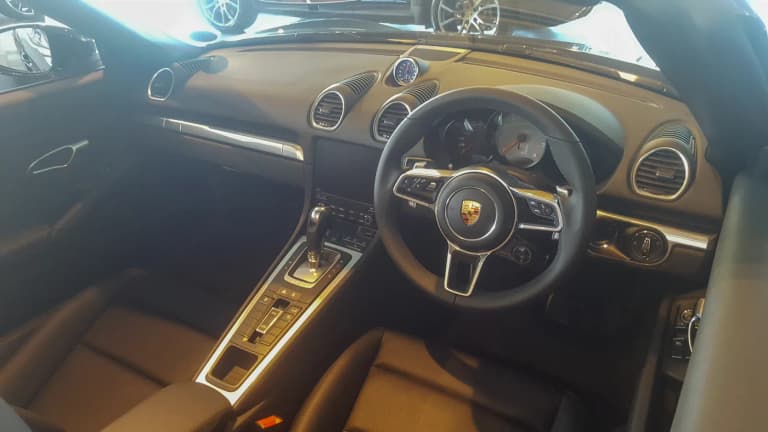 Porsche 718 Boxster interior with the Sport Chrono mode dial on the steering wheel and the dashboard clock