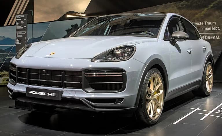 Silver-gray Porsche Cayenne Turbo GT on a show stand with gold wheels