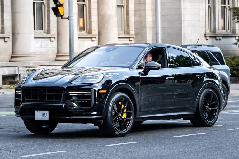 Black facelift Porsche Cayenne Turbo GT driving on a city street, front three-quarter view