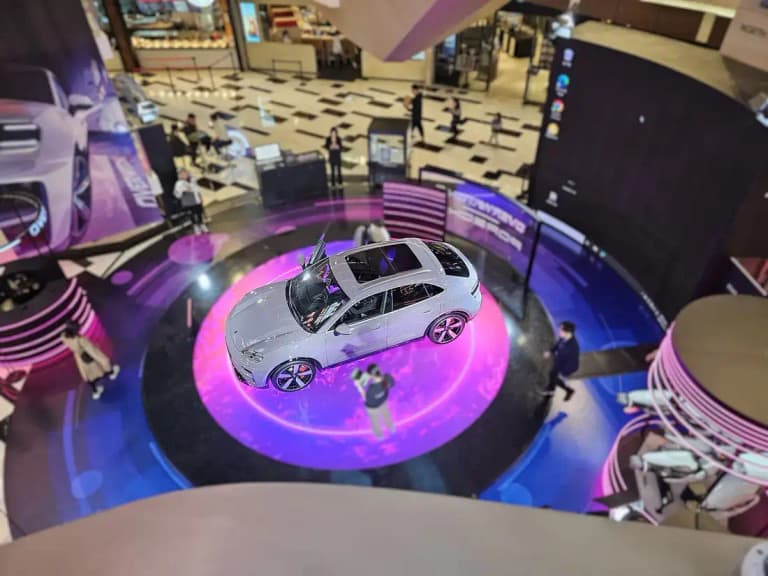 Overhead view of a gray Porsche Macan EV showing the glass roof and long hood