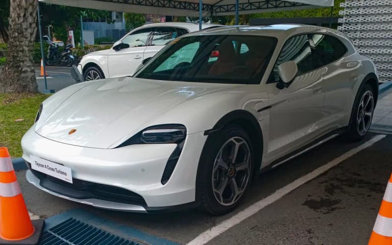 White Porsche Taycan 4 Cross Turismo front three-quarter view showing body cladding and roof rails
