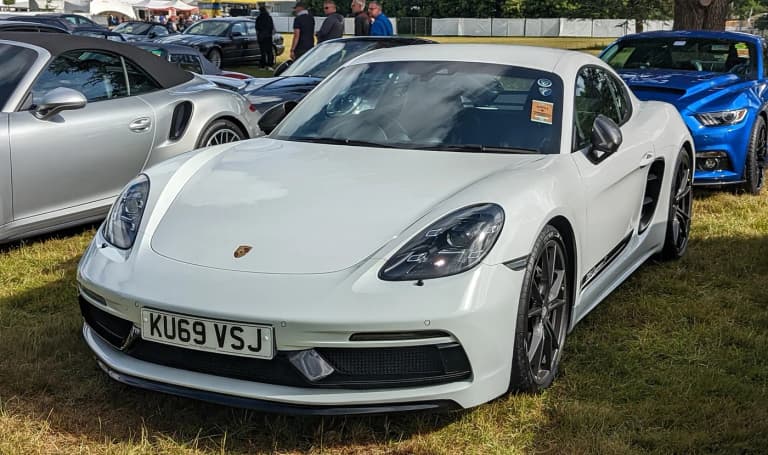 White Porsche 718 Cayman T at a car show, front three-quarter view