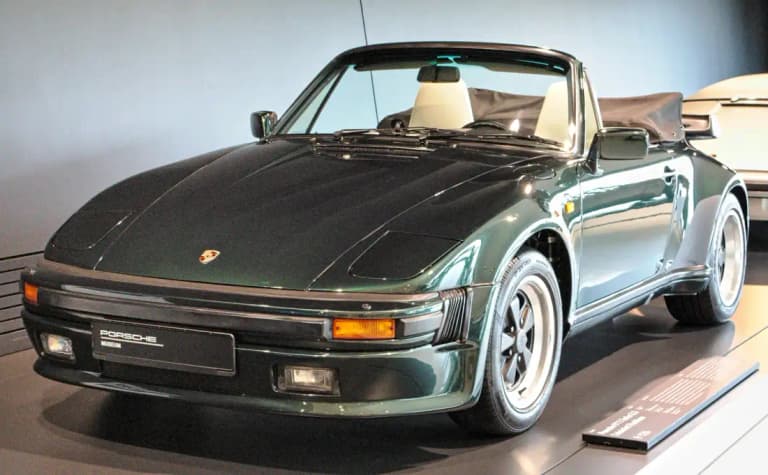 Dark green Porsche 911 Turbo 3.3 Cabriolet Flachbau on display in the Porsche Museum, showing the sloping nose and pop-up headlights