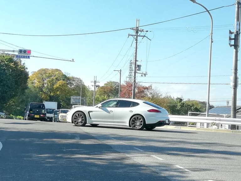 White first-generation Porsche Panamera 4 Edition seen from the side on a Japanese road.