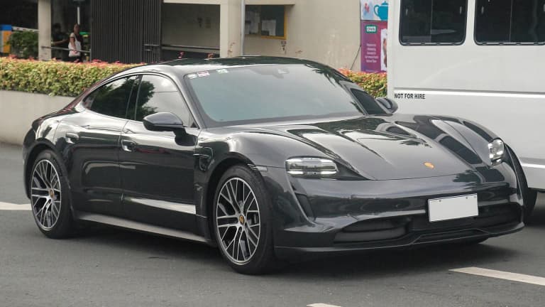 Black Porsche Taycan Turbo sedan parked beside a street.