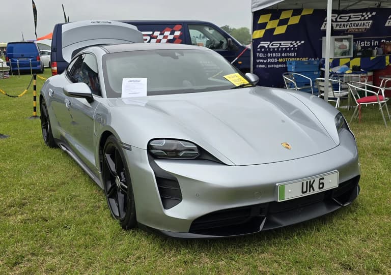 Silver Porsche Taycan Turbo sedan viewed from the front at a car event.