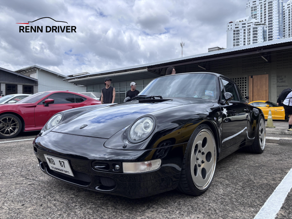 Black 993 Carrera with aero kit and dish wheels, front three-quarter view.