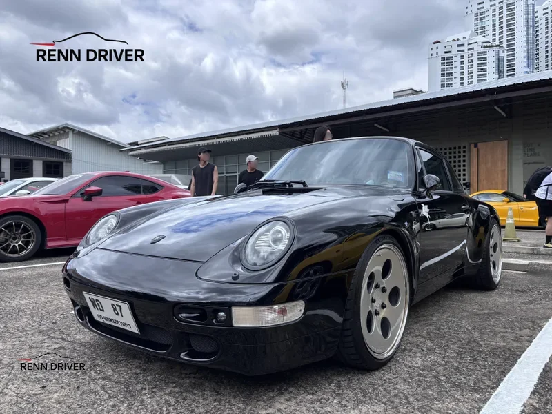 Black 993 Carrera with aero kit and dish wheels, front three-quarter view.