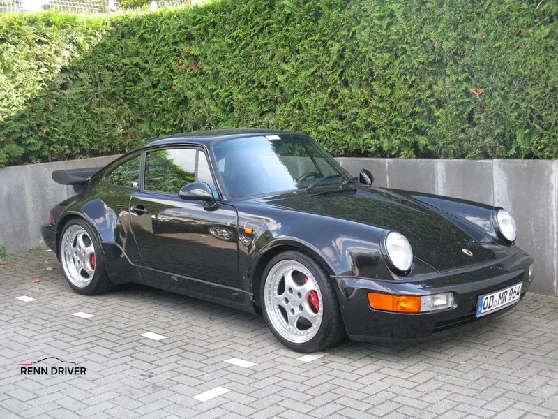 Porsche 911 964 Turbo parked on street, showcasing wide fenders and classic 1990s styling