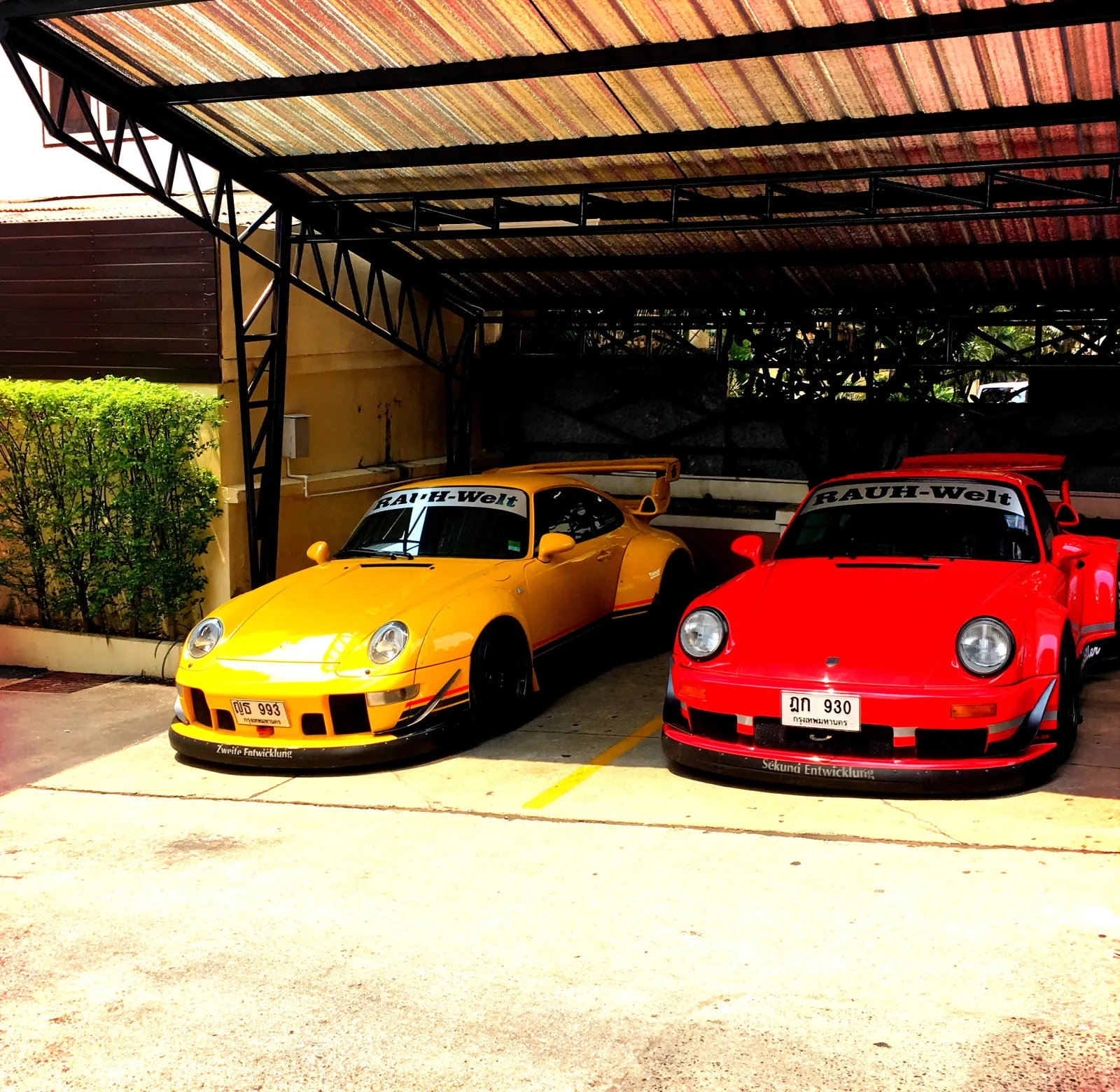 Two modified Porsche sports cars, one yellow and one red