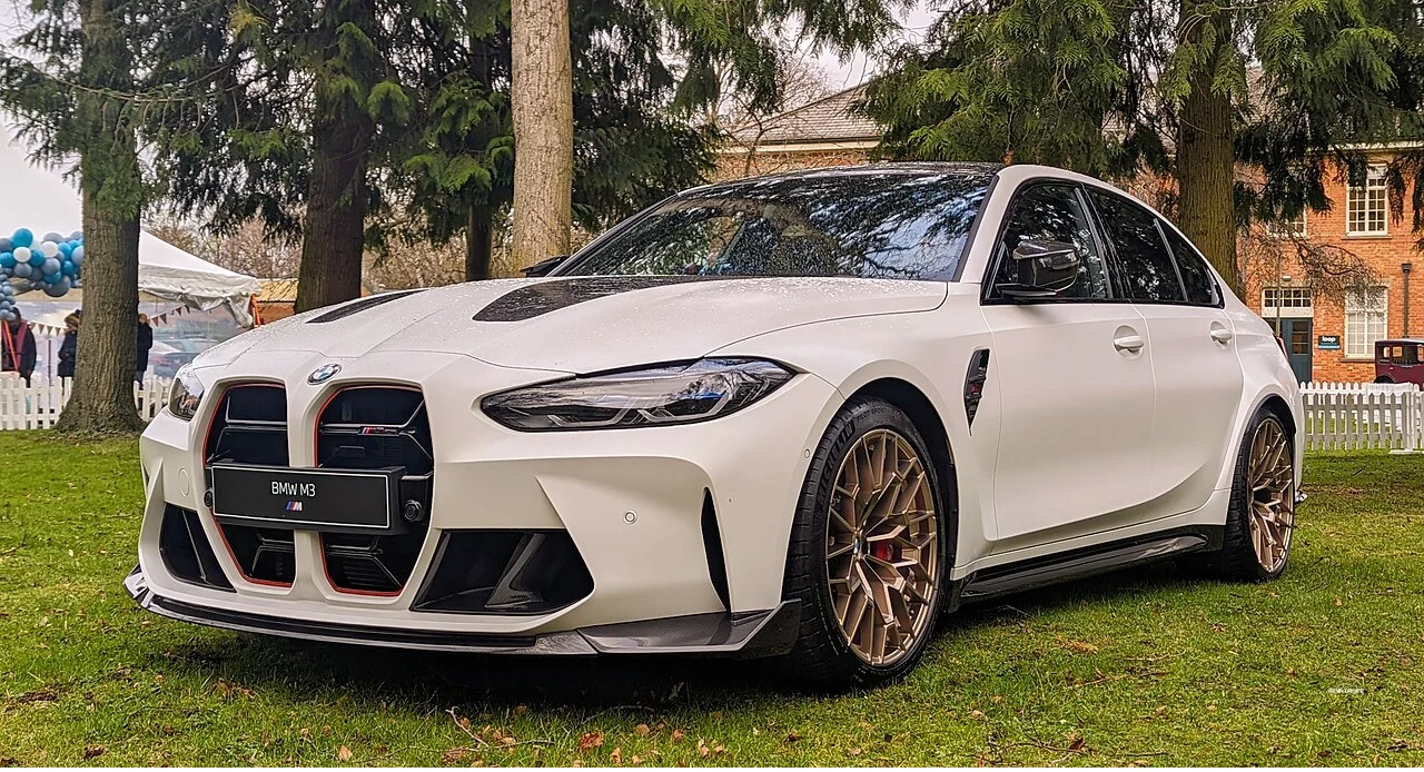 White BMW M3 CS with bronze wheels on grass