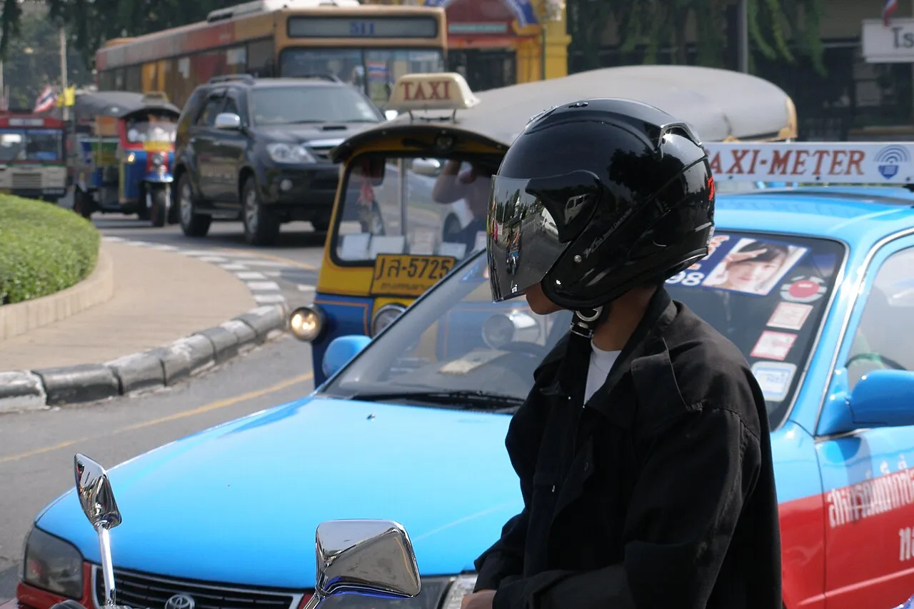 Bangkok street with taxis, tuk tuks, and motorbikes