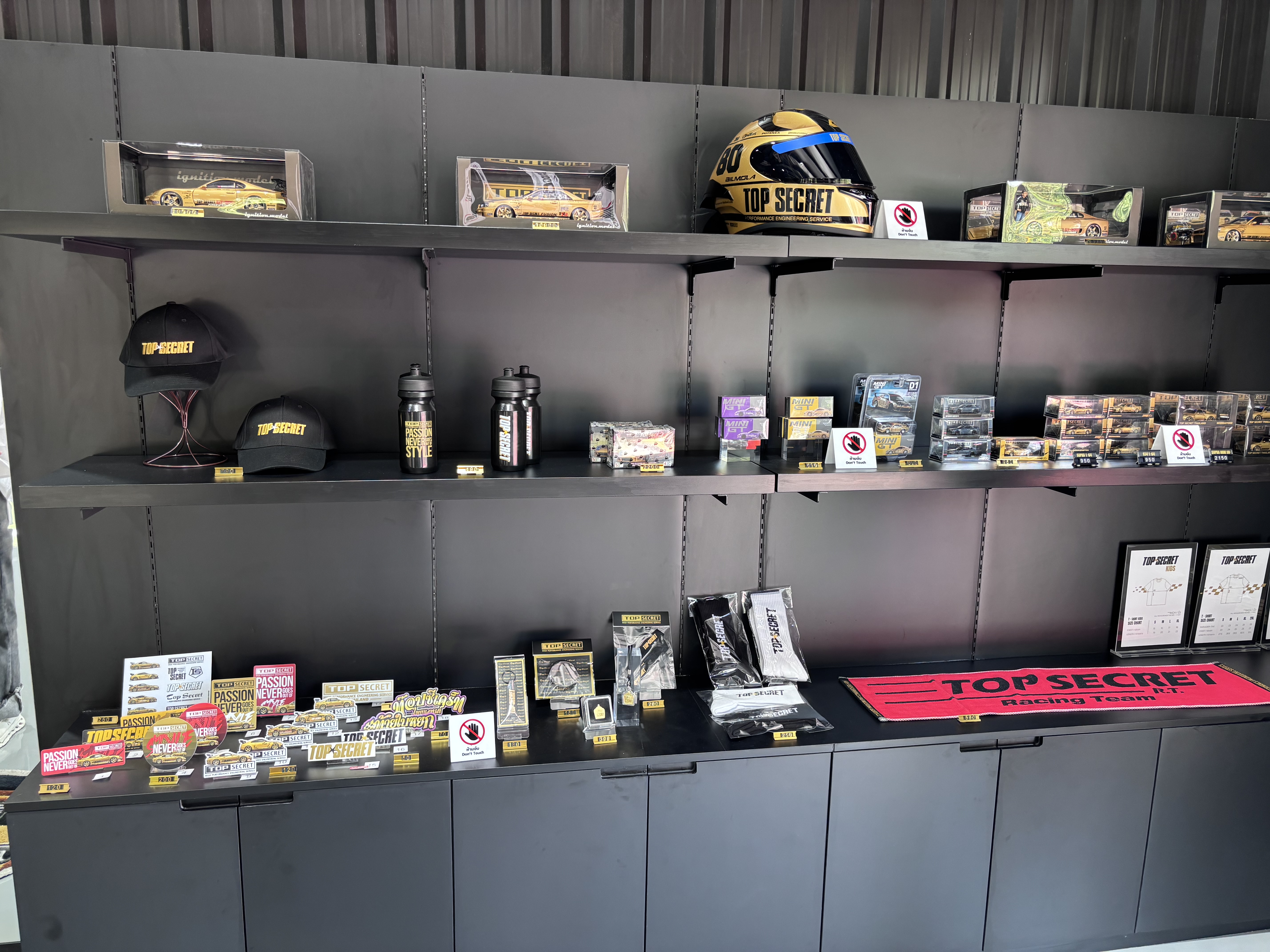 Top Secret merchandise shelf with helmets, caps, and diecast models